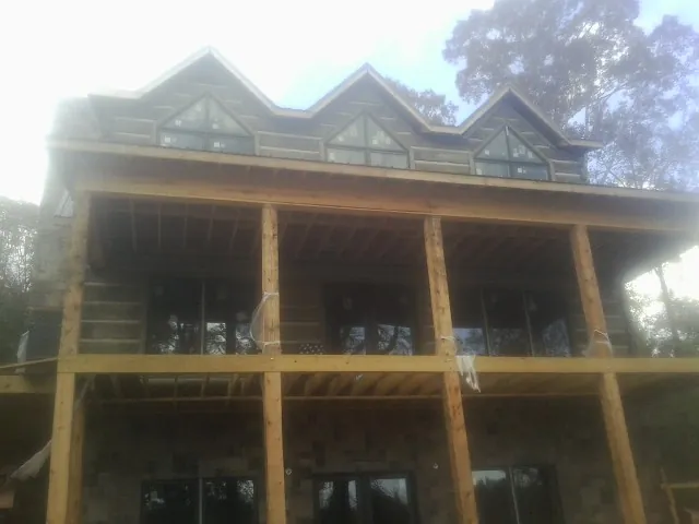Dormers and porch framing on a large log home under construction — Roof Coating work by our crew in Irwin