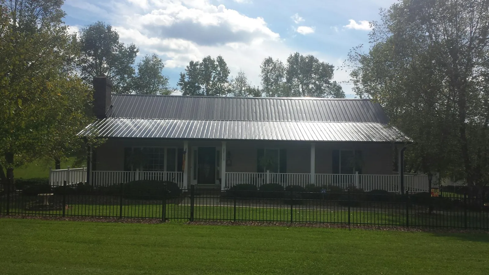 Gray metal roof on a brick ranch with a full width front porch — Gutter Guard Installation work by our crew in Irwin