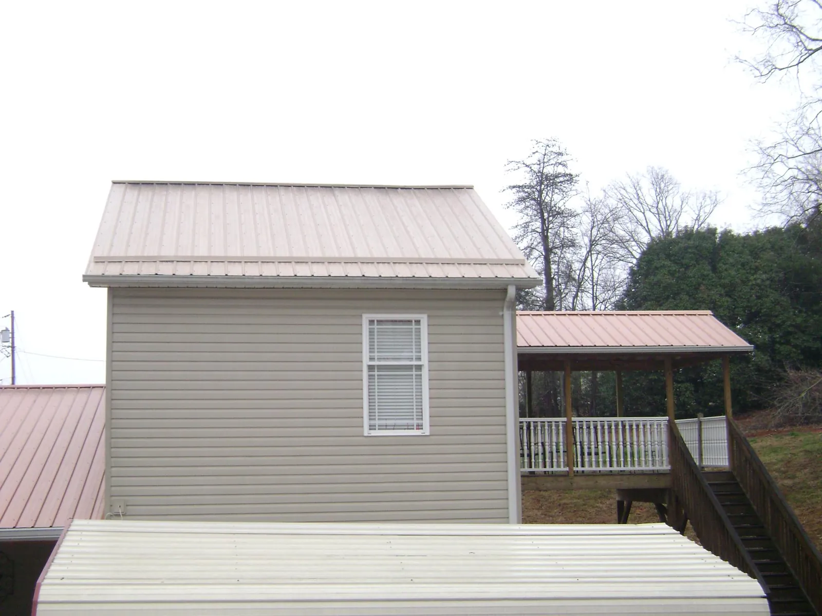 Tan metal roofs on a two story addition and attached porch, from a Roof Replacement job in Irwin